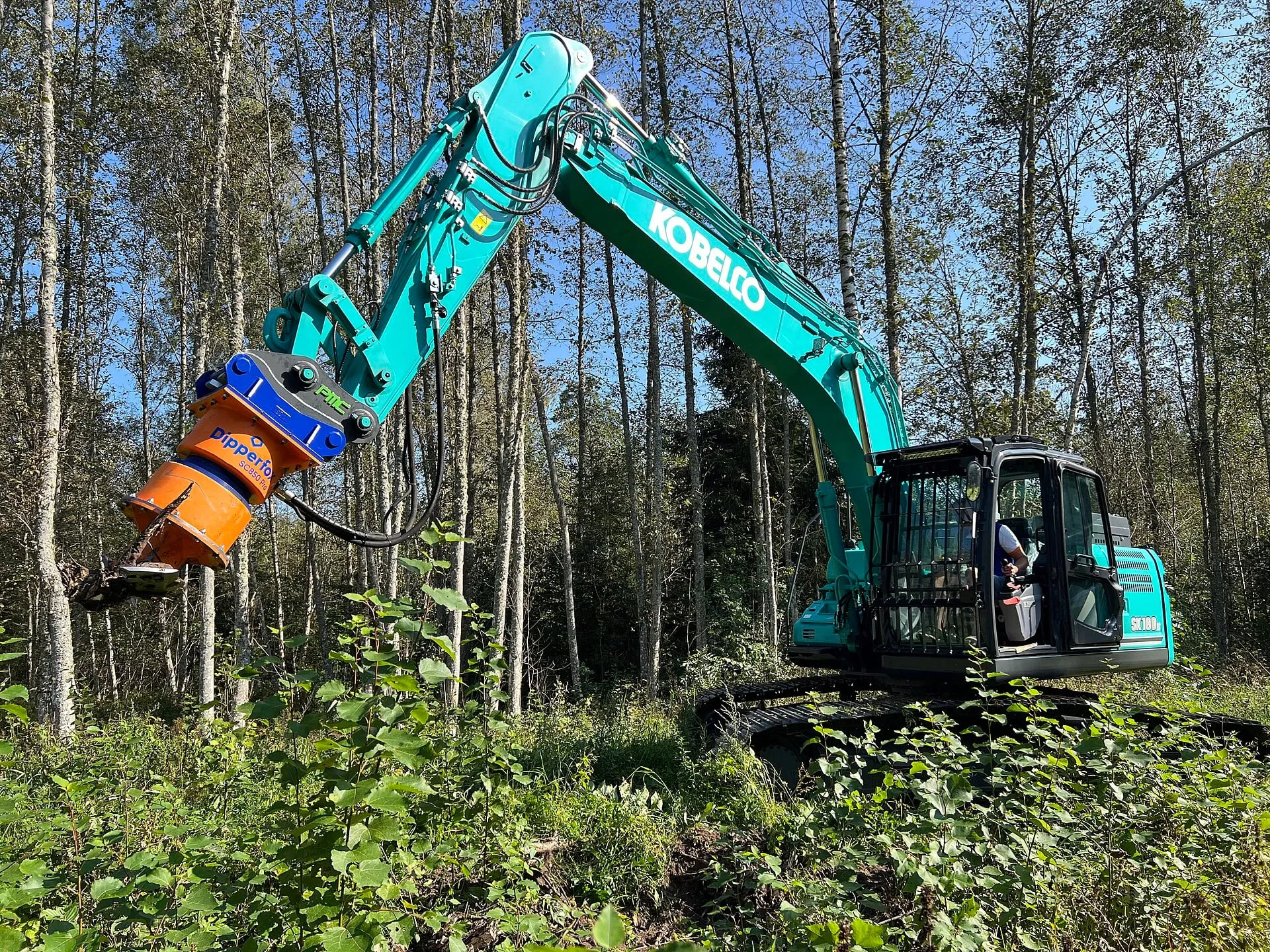 A stump grinder head mounted on an excavator, clearing woodland
