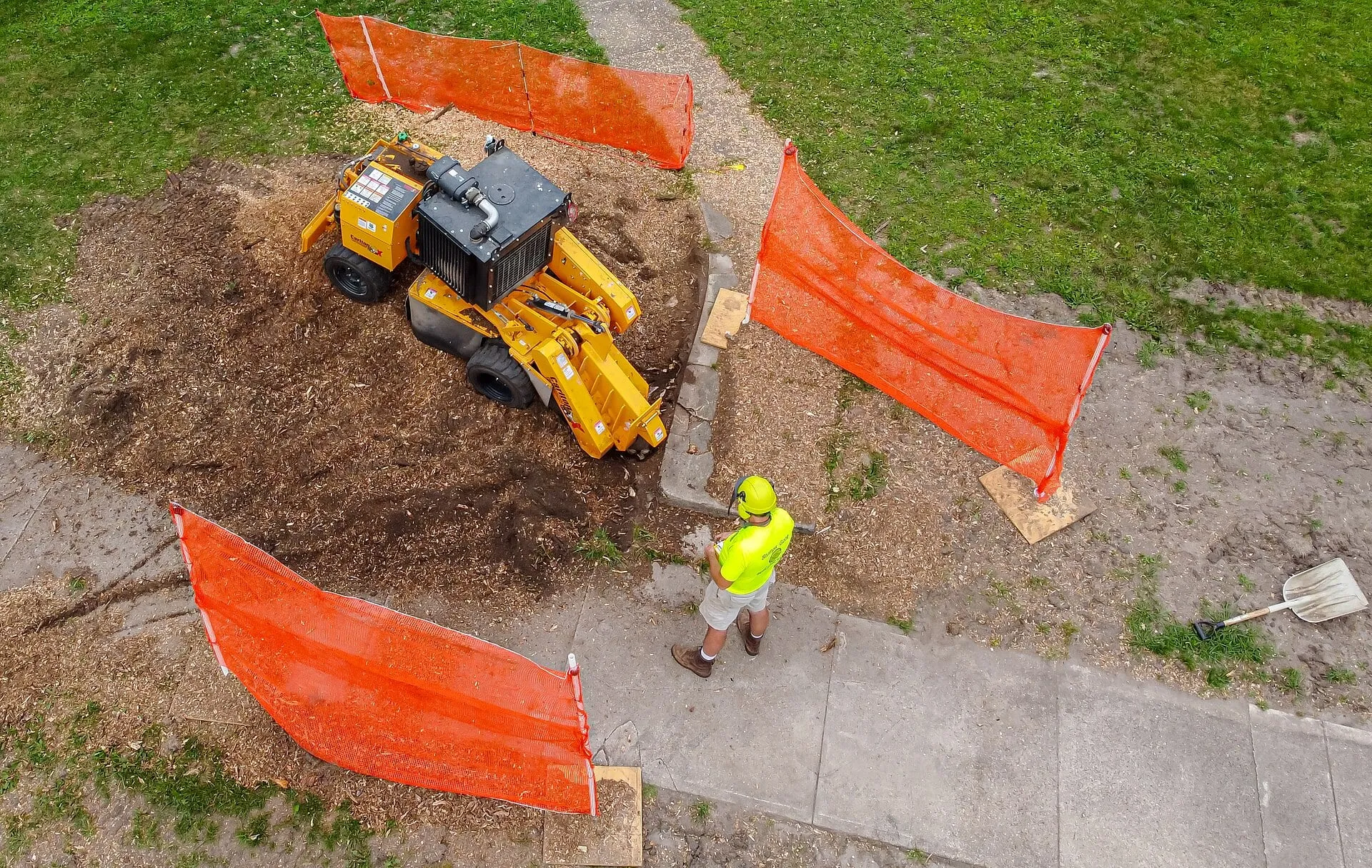 Aerial view of a compact stump grinder working in a strip of lawn