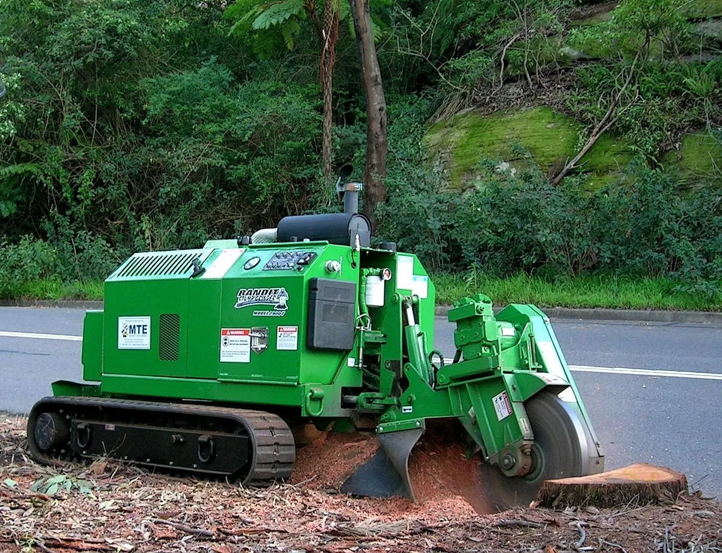 A tracked stump grinder working a stump at the roadside
